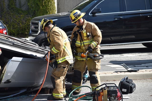 Imagem dois bombeiros civis resgatando vitimas de um acidente de carro.